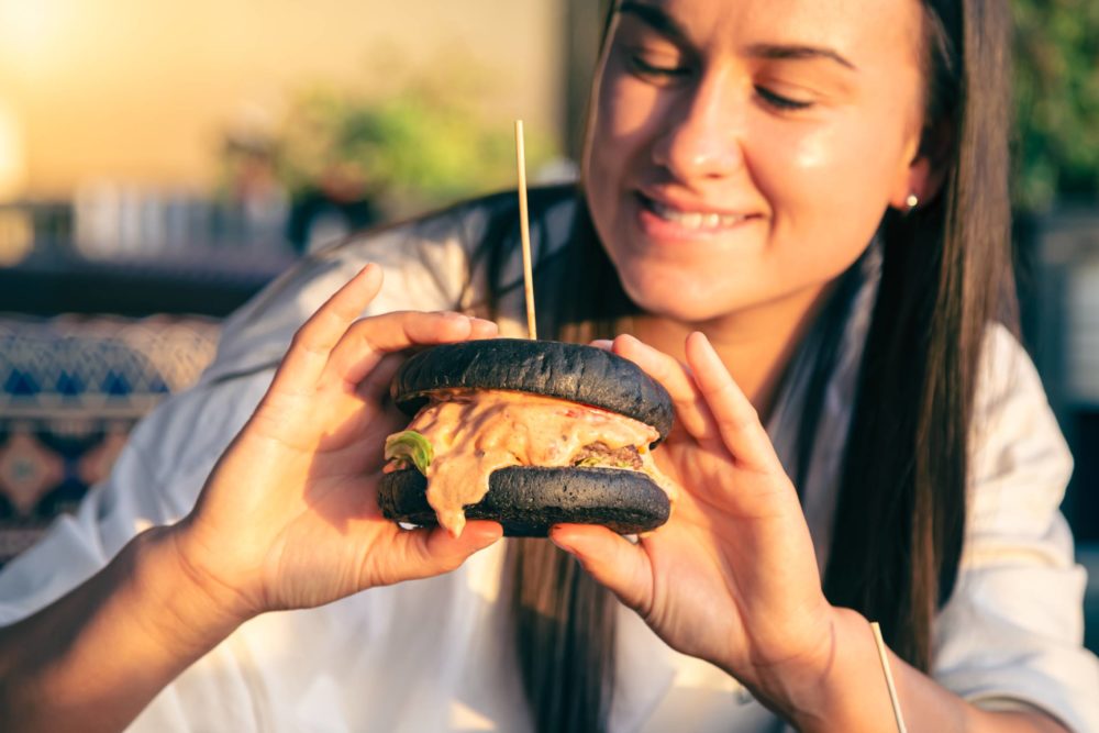 young-woman-eating-burger-street-cafe-close-up-1-1000x667 - Dónde comer hamburguesas en Madrid: precios y ubicación