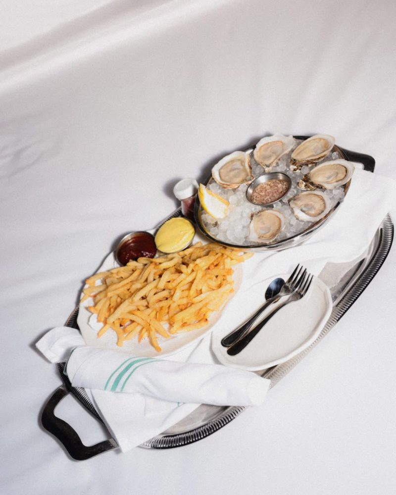 Self-care-means-enjoying-oysters-and-fries-in-bed.__Book-a-weeknight-staycation-this-summer-and-treat-yourself.-1-800x1000 - Wythe Hotel, el hotel boutique en Brooklyn con una llave Michelin