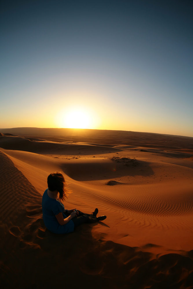 a-woman-sitting-on-sands-watching-the-sunset-copia-667x1000 - Omán, equilibrio perfecto entre adrenalina y calma