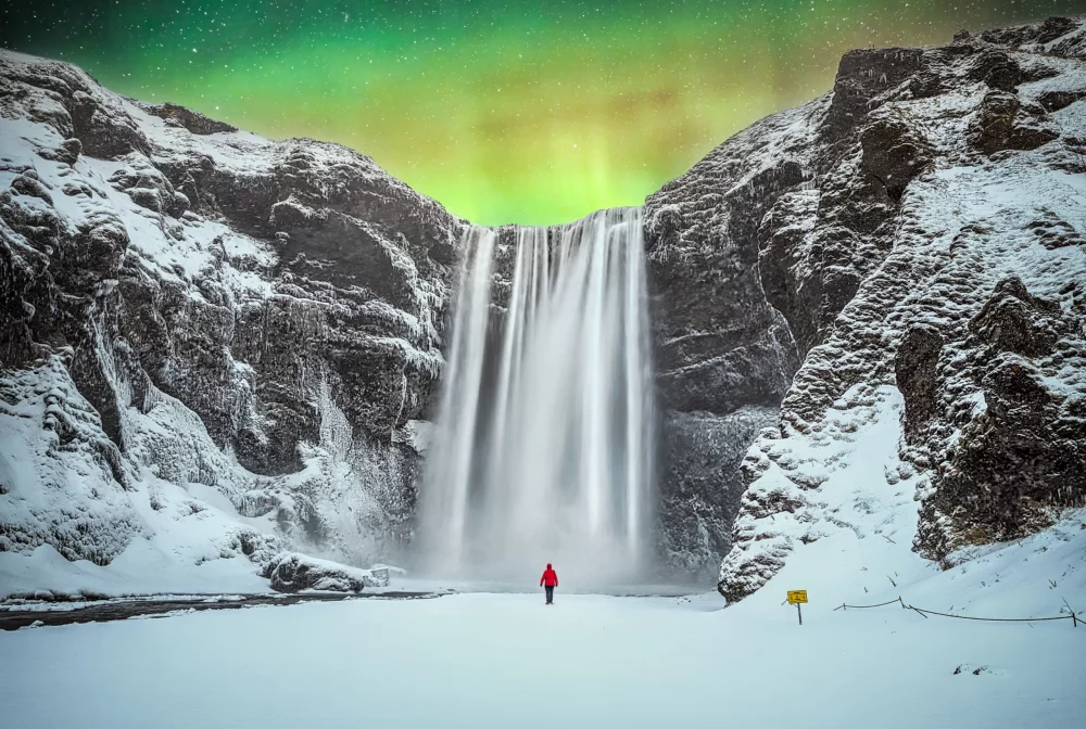 auroras-boreales-sobre-cascada-de-Skogafoss-1000x672 - Tres destinos helados para experimentar la magia —y el desafío— del invierno Ártico